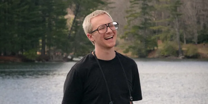 Working photographer laughing beside a forest lake