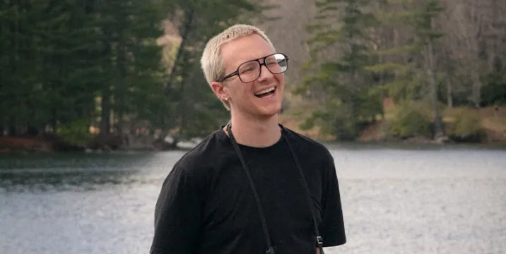 Working photographer laughing beside a forest lake